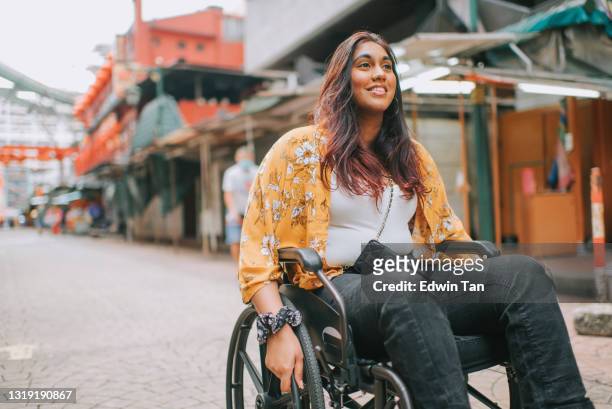 aziatische indische mooie vrouw met handicap die rolstoel gebruikt die de binnenstad in kuala lumpur onderzoekt - wheelchair stockfoto's en -beelden