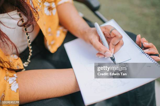asian indian female with disability on wheelchair drawing on pad at city street - free hand sketch street stock pictures, royalty-free photos & images