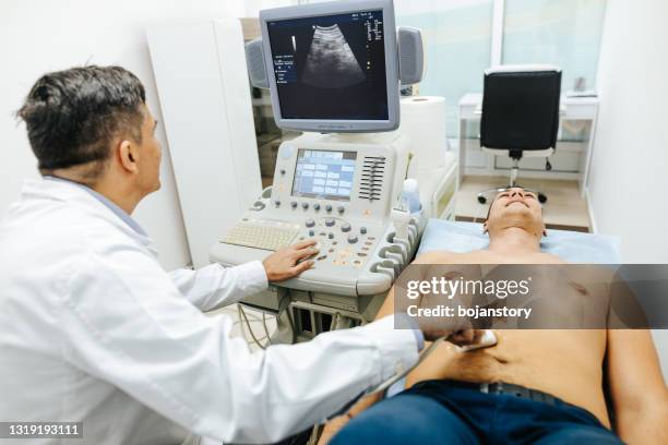 jonge mannelijke patiënt die echografisch onderzoek van buik in medische kliniek heeft - liver stockfoto's en -beelden