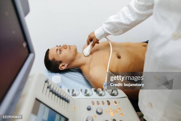 doctor examining thyroid gland with ultrasound machine in hospital - thyroid exam stock pictures, royalty-free photos & images