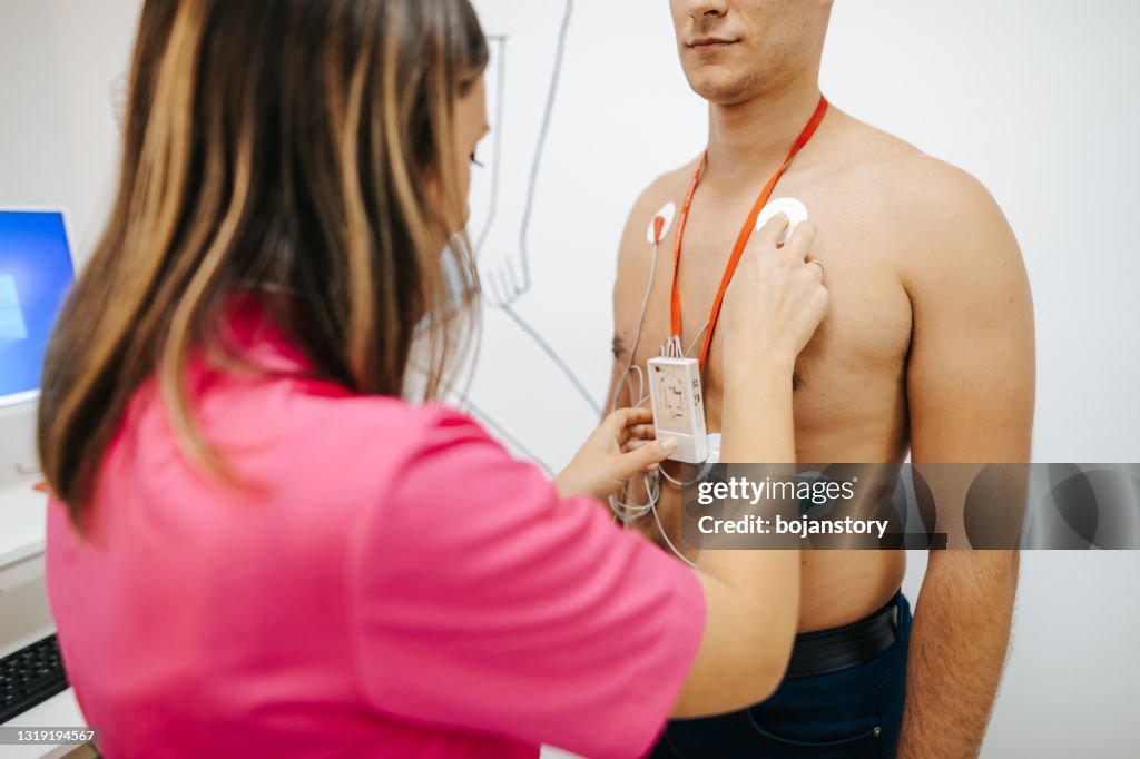 Preparing young male patient for heart stress test on treadmill