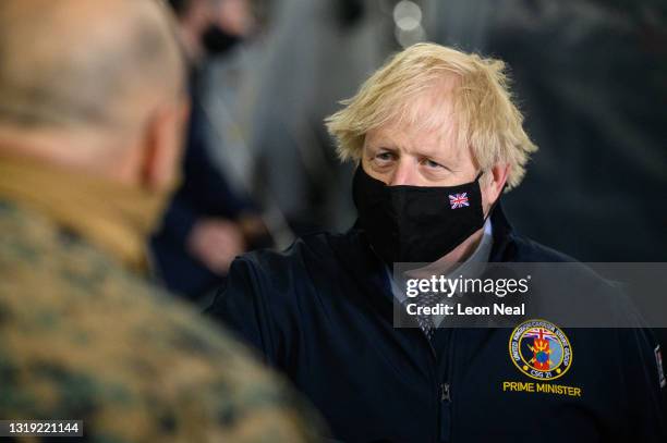Prime Minister Boris Johnson speaks with ground crew next to a Merlin Mk2 helicopter during a visit to HMS Queen Elizabeth aircraft carrier on May...