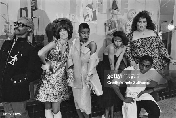 Group of young people dressed in New Wave fashions, with a young man wearing heavy rimmed glasses, a black jacket with a white silhouette of a...