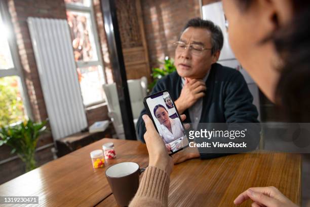 elderly couple cell phone use online to see a doctor - tonsille stock-fotos und bilder