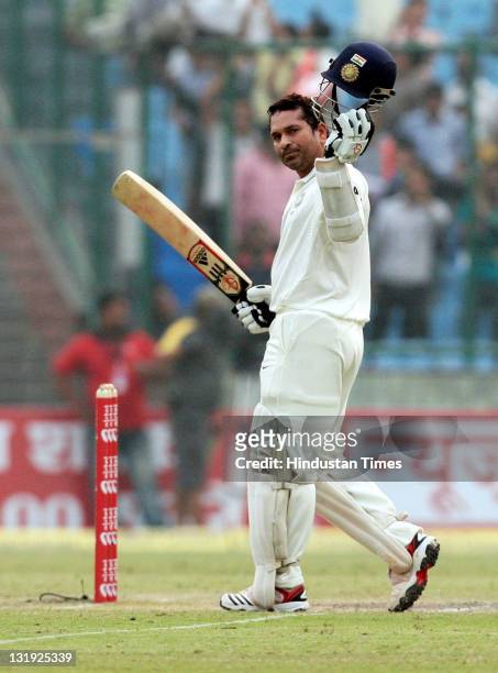 Sachin Tendulkar raises his bat and helmet after completing 15000 runs in test cricket, highest ever by any batsman during the third day of the first...