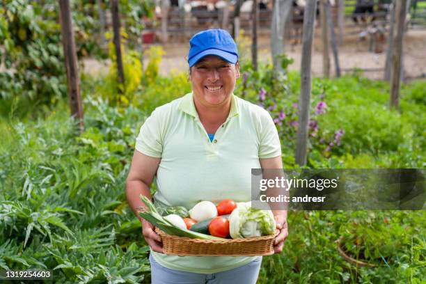 happy woman carrying a basket of homegrown produce vegetables - farm worker woman stock pictures, royalty-free photos & images