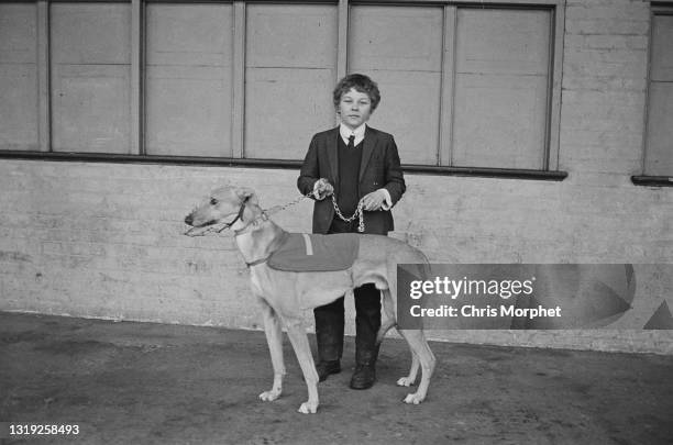 Boy with a Greyhound dog awaiting for a track trial at Hackney Racetrack, London, UK, 10th April 1968.