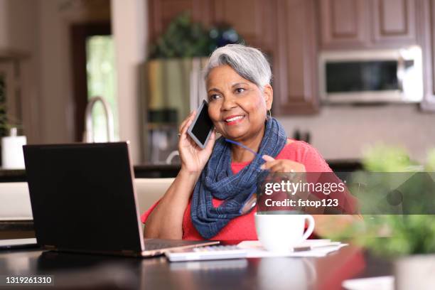 femme adulte aîné utilisant le téléphone et l’ordinateur portatif à la maison. - call us photos et images de collection