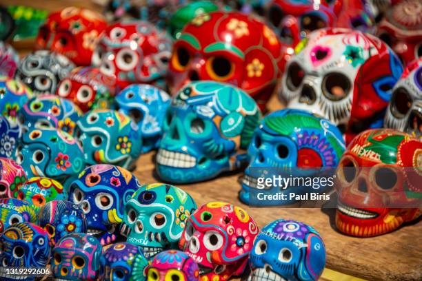 colorful (colourful) traditional mexican/hispanic ceramic pottery  skulls on display at a market in mexico - mexican skull stock pictures, royalty-free photos & images