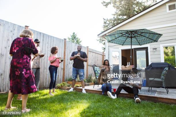 uitgebreide familie hereniging samen voor maaltijd - backyard barbeque stockfoto's en -beelden