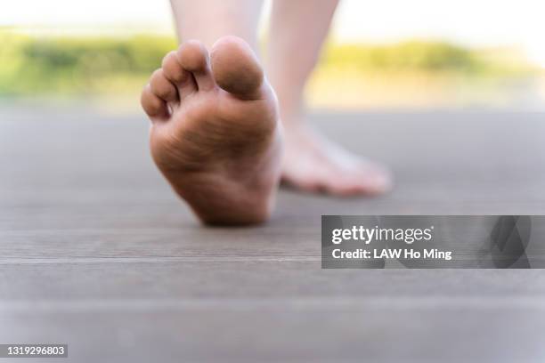 a man walking barefoot on a wooden board - barefoot foto e immagini stock