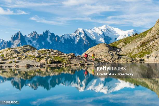 hikers reflected in lac blanc on the tour du mont blanc trekking route in the french alps near chamonix - mont blanc massiv stock-fotos und bilder