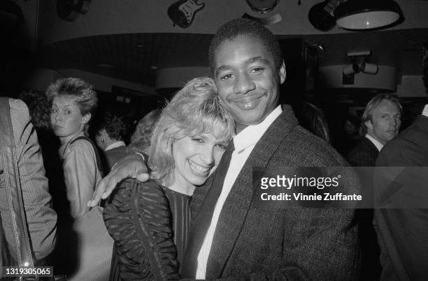 American saxophonist and composer Branford Marsalis, wearing a blazer and tie with a white shirt, with his arm around the shoulder of an unspecified...