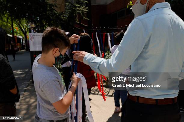 Principal Ben Geballe helps a student put up ribbons with messages of peace, love and hope at Sun Yat Sen M.S. 131 on May 21, 2021 in New York City....