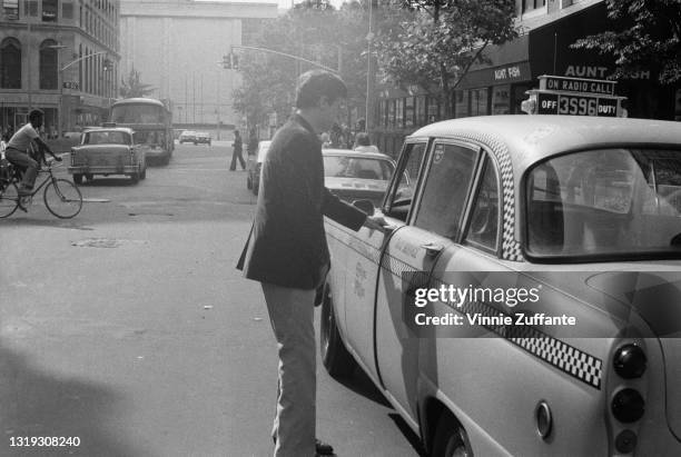 American actor Robert De Niro opening the driver's door on his Checker A series sedan cab on the set of the film 'Taxi Driver,' in New York City, New...