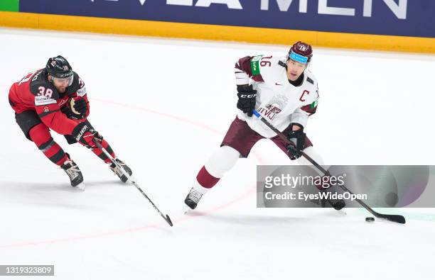 Kaspars Daugavins of Latvia against Mario Ferraro of Canada during the 2021 IIHF Ice Hockey World Championship group stage game between Canada and...