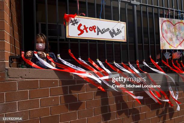 Parent Coordinator Christina Pun puts up ribbons with messages of peace, love and hope in front of Yung Wing School P.S. 124 on May 21, 2021 in New...