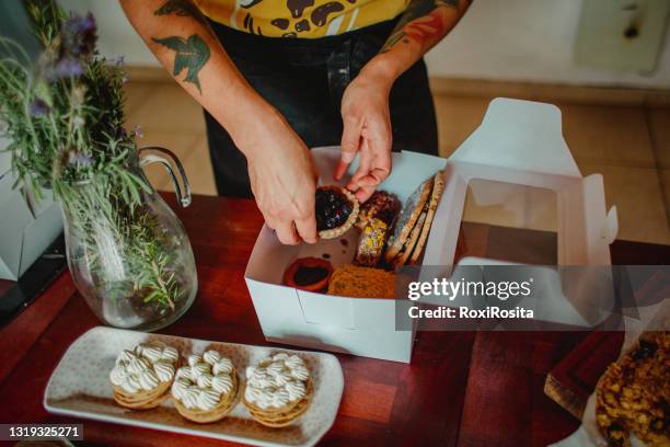 woman's hands arranging desserts in a box. on the table variety of cakes. - cupcake box stock pictures, royalty-free photos & images