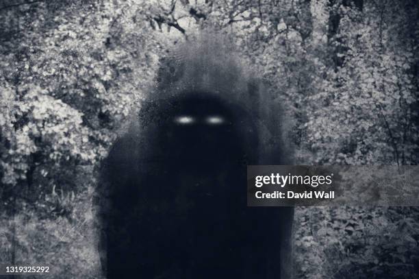 a dark scary concept. of a mysterious supernatural figure with glowing eyes looking at the camera. with a grunge, textured edit - demon stock pictures, royalty-free photos & images