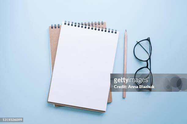note pad with blank page, eyeglasses and pencil over blue background. greeting card for spring holidays, mother's day. - index card stockfoto's en -beelden
