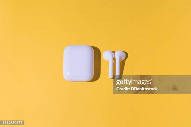 trendy cordless white headphones on yellow background - apple white background stock-fotos und bilder