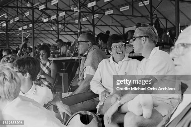 American tennis player Billie Jean King with her legs across the lap of her husband, the American founder of World Team Tennis Larry King, in the...