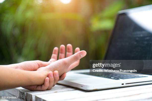 woman holding her wrist pain from using computer. office syndrome - rheuma stock-fotos und bilder