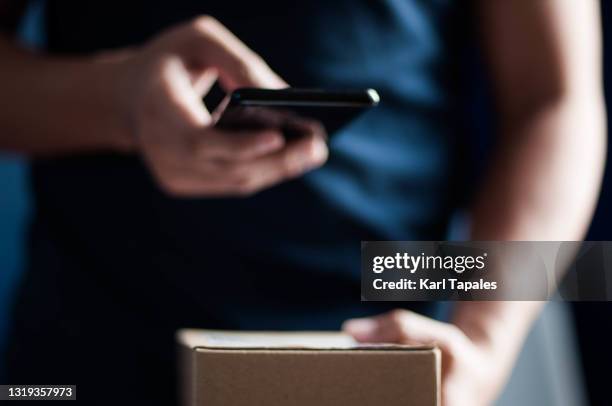 a southeast asian young adult male scanning barcode on a small carton box package - scanner stock stock pictures, royalty-free photos & images