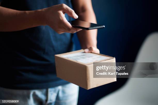 a southeast asian young adult male scanning barcode on a small carton box package - returning product stock pictures, royalty-free photos & images