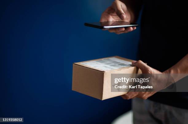 a southeast asian young adult male scanning barcode on a small carton box package - scanner stock stock pictures, royalty-free photos & images