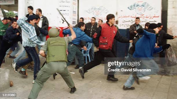 An Israeli Border Policeman lashes out at fleeing Palestinians with his stick as clashes erupt outside Jerusalem''s Old City December 15, 2000 prior...