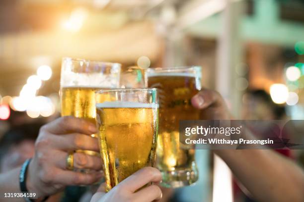 friends toasting with glasses of light beer at the pub. beautiful background of the beer fest. a group of young people while relaxing at the bar. fine grain. soft focus. shallow dof. - oktoberfest fotografías e imágenes de stock