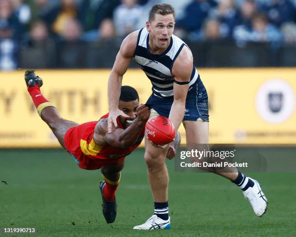 Joel Selwood of the Cats handballs whilst being tackled by Touk Miller of the Suns during the round 10 AFL match between the Geelong Cats and the...