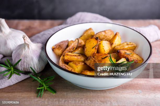 roasted potatoes with rosemary in a blue bowl on wooden background - baked potato stock pictures, royalty-free photos & images