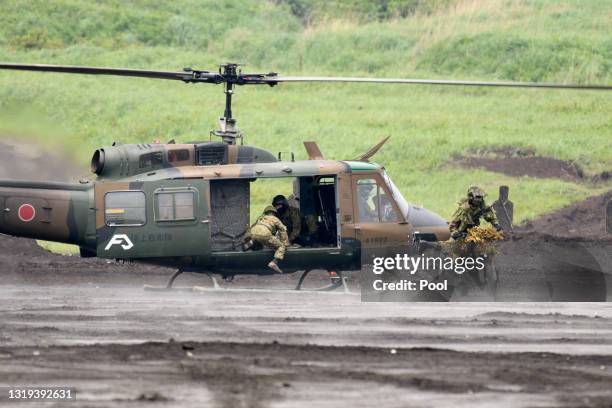 Japan's Ground Self-Defense Forces soldier ride a motorbike past a helicopter during a live fire exercise at JGSDF's training grounds in the East...