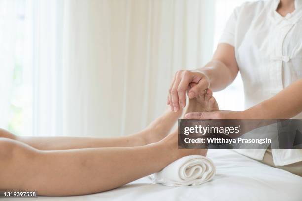 close-up of female hands doing foot massage - réflexologie photos et images de collection