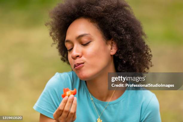 美しいアフリカ系アメリカ人の女性は新鮮なイチゴで楽しんでいます。 - biting ストックフォトと画像