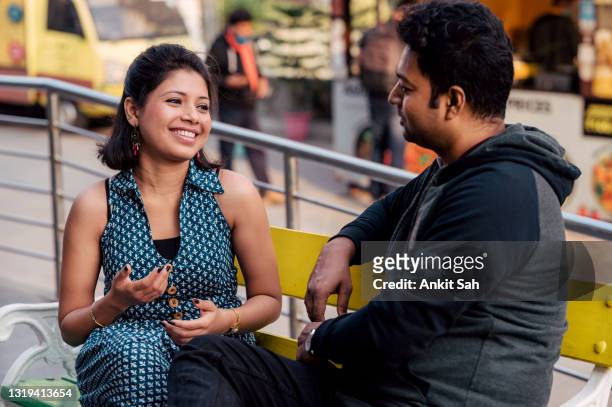 romantic indian couple sitting on bench and talking to each other - girlfriend stock pictures, royalty-free photos & images