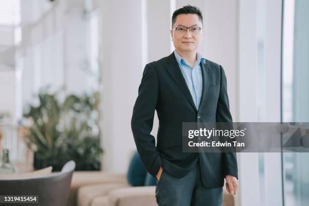 portrait asian chinese successful businessman looking at camera smiling with confidence in office - businessman hands in pockets stock pictures, royalty-free photos & images