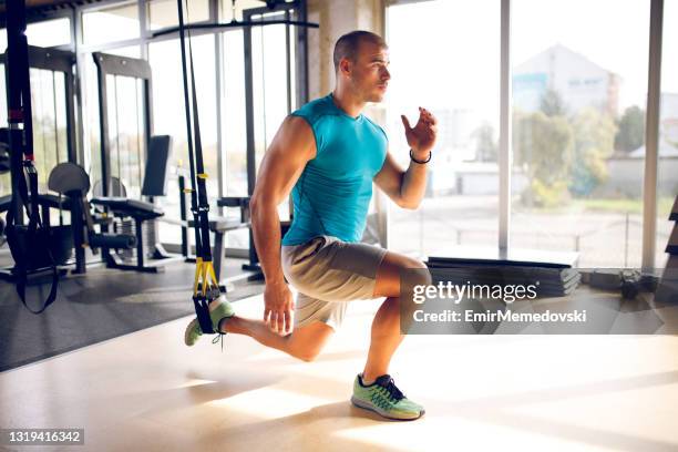 man doing leg exercises with suspension straps at gym - suspension training stock pictures, royalty-free photos & images