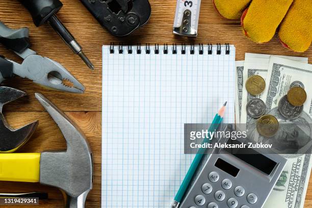 tools for building a house or repairing an apartment, on a wooden background or table. workplace of the foreman. the theme of home and professional repair and construction. notepad and pen, calculator and cash dollars. - service level high stock pictures, royalty-free photos & images