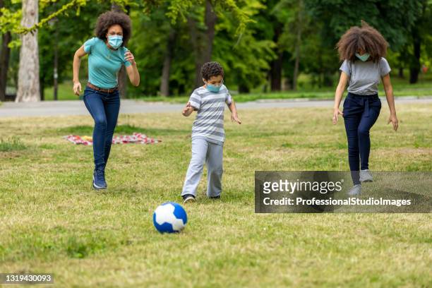 happy young familia afroamericana está jugando con pelota de fútbol al aire libre en la naturaleza. - football face mask fotografías e imágenes de stock
