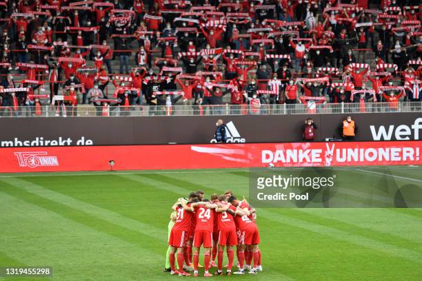 Union Berlin players huddle as fans hold up scarves prior to the Bundesliga match between 1. FC Union Berlin and RB Leipzig at Stadion An der Alten...