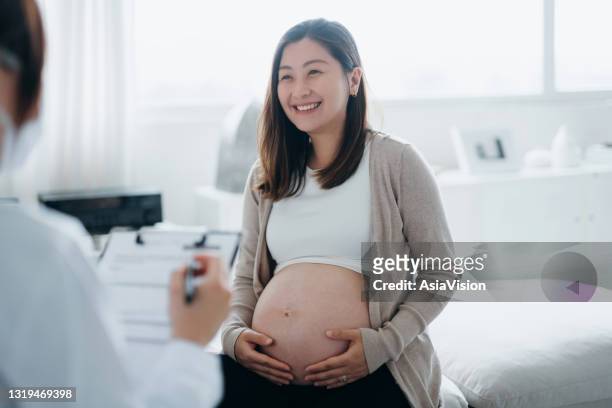 mujer embarazada asiática sonriente que tiene una consulta con una doctora durante su chequeo de rutina en una clínica. chequeos, pruebas y exploraciones para asegurar un embarazo saludable tanto para la madre como para el feto. estilo de vida saludable  - pelvic exam fotografías e imágenes de stock