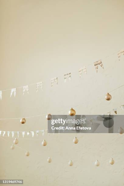 garlands with paper and balls on strings against textured white wall. new year celebration concept. copy space for your design - bauble white background foto e immagini stock