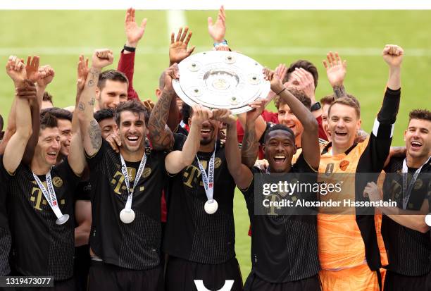 Javi Martinez, Jerome Boateng and David Alaba of FC Bayern Muenchen lift the Bundesliga Meisterschale Trophy in celebration with team mates following...