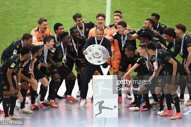 Hans-Dieter Flick, Manager of FC Bayern Muenchen lifts the Bundesliga Meisterschale Trophy in celebration with his players following the Bundesliga...