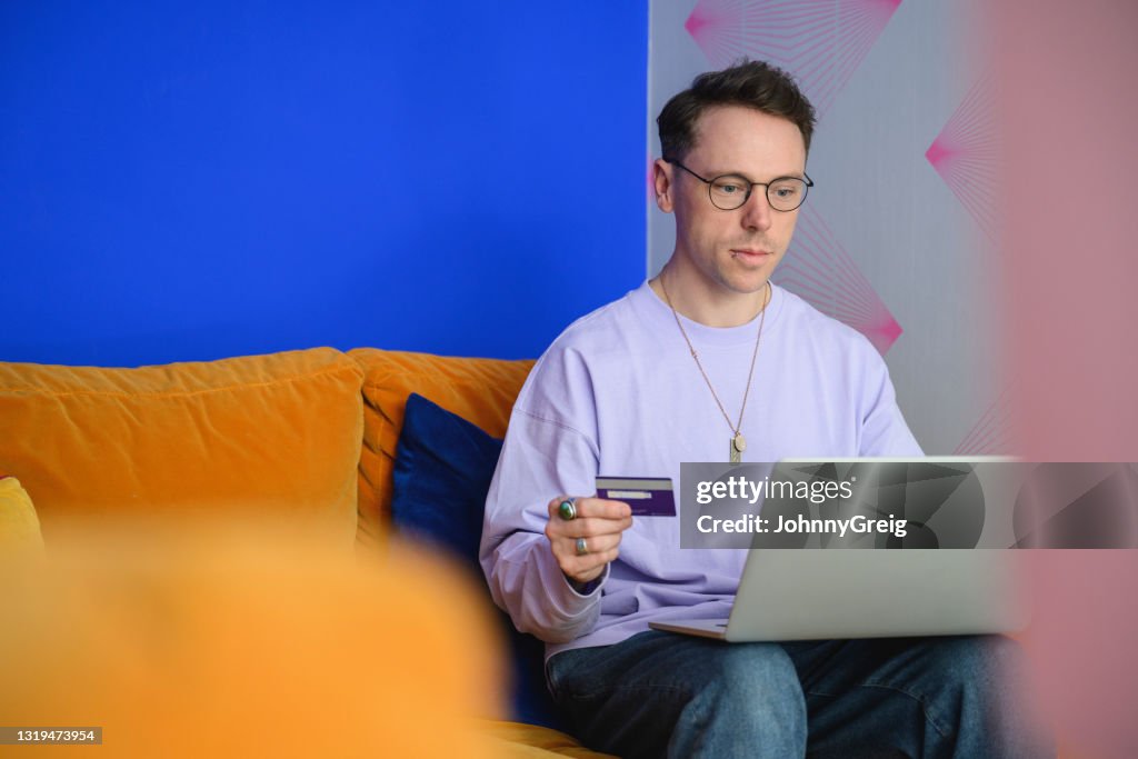 Mid 30s man at home using credit card for online shopping