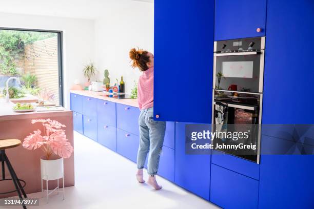 mid adult caucasian woman reaching into refrigerator - refrigerator door stock pictures, royalty-free photos & images
