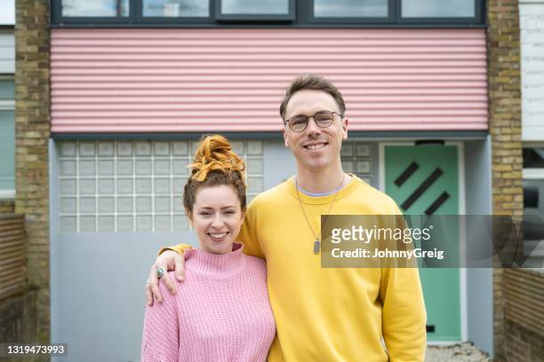 proud mid 30s home owners with arms around each other - mid adult couple stock pictures, royalty-free photos & images